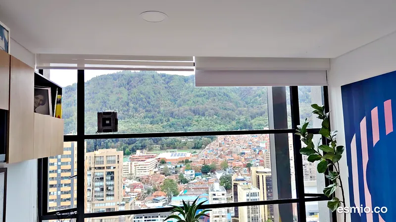 Robot limpia vidrios trabajando sobre un ventanal con vista a los cerros orientales de Bogotá