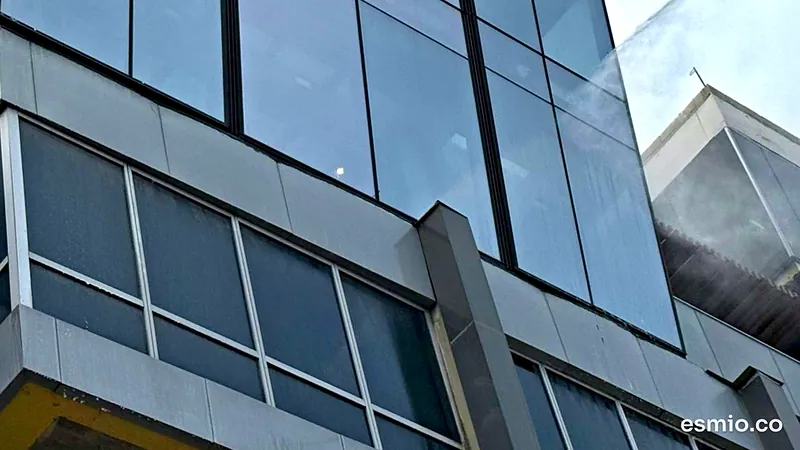 Rocío de agua del dron sobre la fachada de vidrio de un edificio durante el lavado