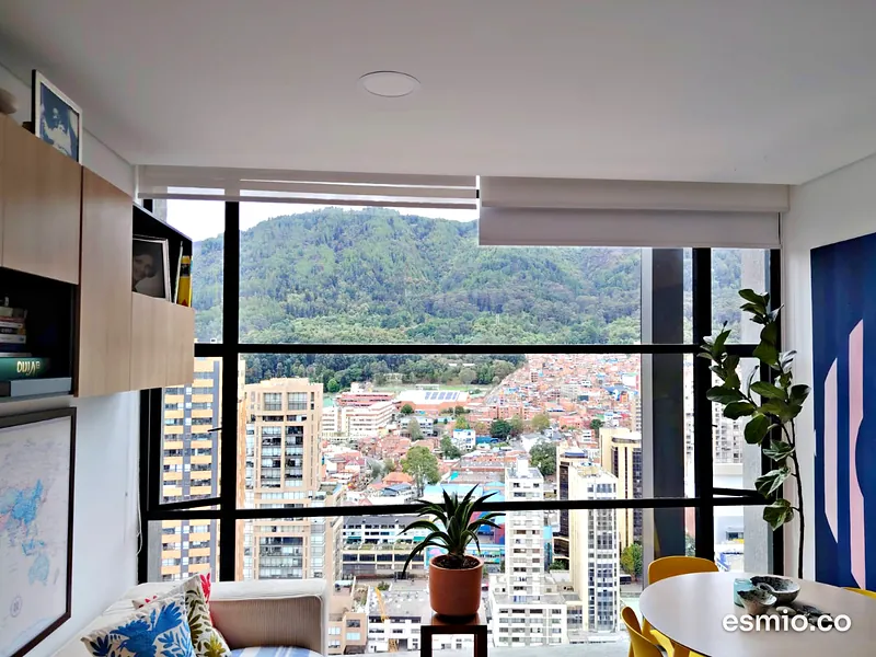 Sala de apartamento con ventanales limpios de piso a techo y vista a los cerros de Bogotá