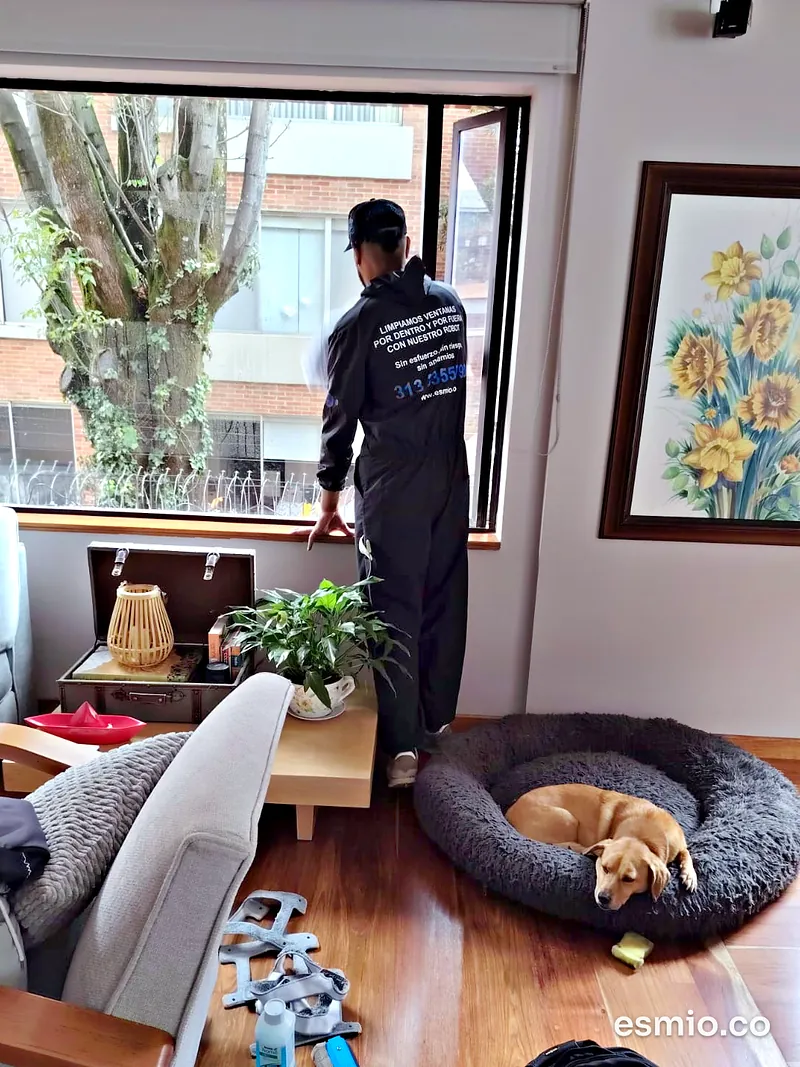 Técnico de Esmio limpiando una ventana a domicilio en un apartamento de Bogotá