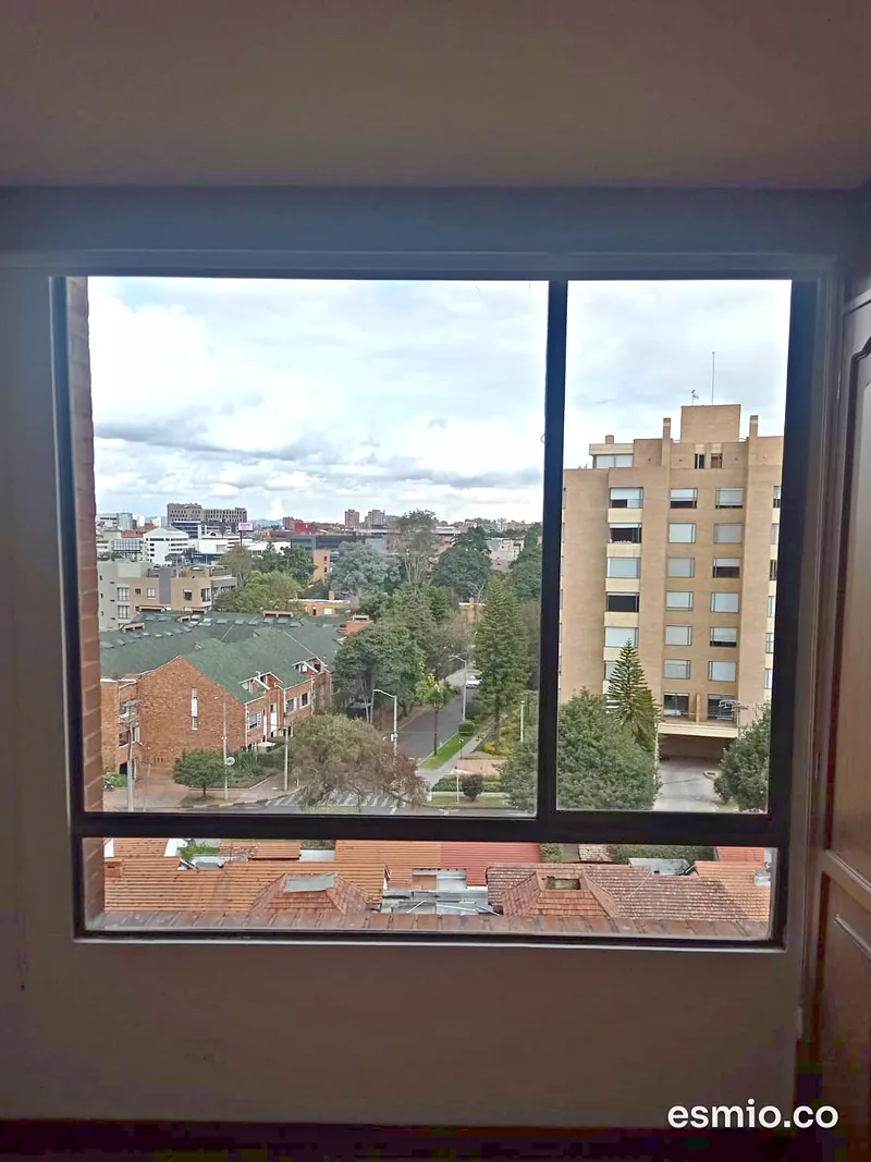 Ventana con los vidrios limpios y vista a un barrio residencial de casas y edificios
