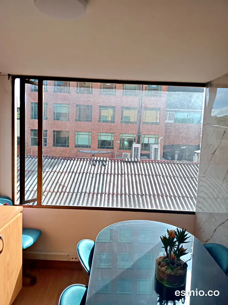 Ventanal con los vidrios limpios junto a una mesa de vidrio, con vista a edificios de ladrillo en Bogotá