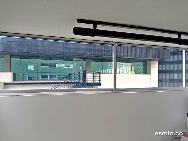 Ventanal de oficina limpio frente a un edificio corporativo de vidrio en Bogotá